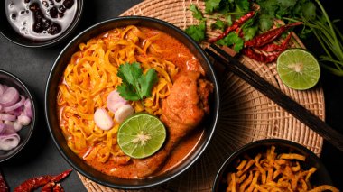 Üst manzara, Khao Soi Kai, baharatlı baharatlı baharatlı köri çorbası tavuk budu ve yanında Asya yemeği. Kuzey Tayland gıda konsepti