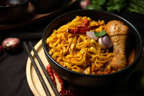 カオソイカイ おいしいとスパイシーなクリーミーな黄色のカレー麺と黒のボウルにチキンドラムスティック箸を提供しています タイ北部料理 — ストック写真