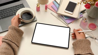 Yakın plan görüntü, rahatlamış kadın güzellik blogcusu dijital tablet kullanıyor, sabah kahvesini yudumlarken çevrimiçi içeriğini oluşturuyor. tablet boş ekran modellemesi.