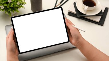Elinde dijital taşınabilir tablet dokunmatik bilgisayarlı bir kadın eli boş bir ekran modeli ve ofis masasının üzerinde stil kalem, yakın plan..