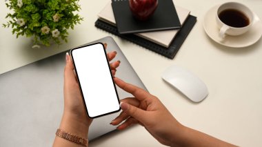 Yakın plan görüntü, seçici odaklı eller, akıllı telefon kullanan bir kadın, cep telefonuyla yazı yazan, cep telefonunu ofis masasının üstünde tutan bir kadın..