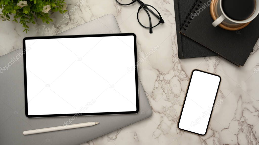 Modern office desk, top view, flat lay with digital tablet and smartphone white screen mockup, office supplies and coffee sup on marble background.