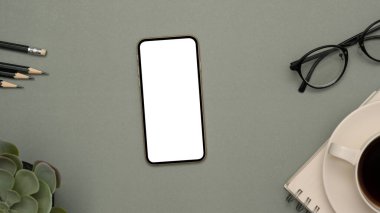 Üst manzara, atölye beyaz ekran modeli, gözlük, kalem, bitki ve kahve fincanı gri arkaplanda..