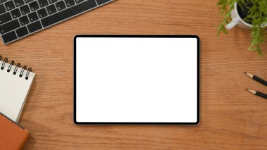 Genel çekim, modern ahşap ofis masası arkaplanı, dijital tablet boş ekran modeli ve ofis aksesuarları..