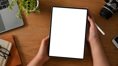 Düz yatıyordu, Top view, kadın fotoğrafçı ya da tablet beyaz ekranı asgari ahşap masasının üzerinde tutan serbest çalışan bir el..