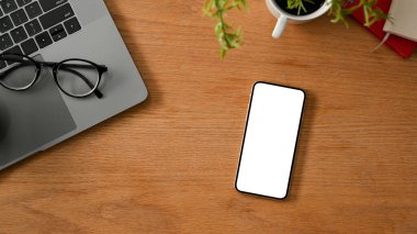 Ofis aksesuarları ile ahşap masada imajınızı görüntülemek için akıllı telefon beyaz ekran modeli. yukarıda