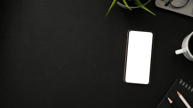 Akıllı telefon beyaz ekran maketi, kahve fincanı, kırtasiye malzemesi, dekor ve montaj için kopyalama alanı olan basit koyu renk arkaplan. en üstteki görünüm