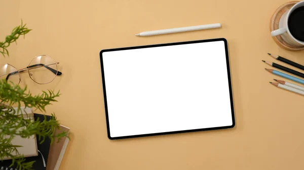 デジタルタブレットタッチパッド付きのワークスペーストップビュー白スクリーンモックアップ コーヒーカップとベージュの背景に装飾 — ストック写真
