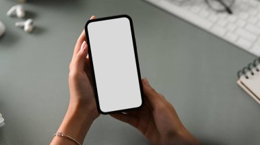 Ofis masasının üzerinde akıllı telefon beyaz ekran maketi tutan bir iş kadını. yakın plan resim