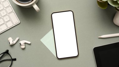 Akıllı telefon beyaz ekran maketi ve modern gri ofis masasında ofis eşyalarıyla iş ve teknoloji geçmişi. en üstteki görünüm