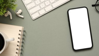 Klavye bilgisayarı, bir fincan sade kahve, sarmal defter, kulaklıklar ve gri arka planda akıllı telefon modeliyle modern iş yeri masası manzarası. düz yat