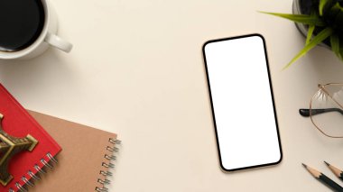 Ofiste çalışma alanı, akıllı telefonlu ofis masası boş ekran maketi, defter, gözlük, kahve fincanı, dekor bitkisi, beyaz arka planda kalem ve boşluk. en üstteki görünüm