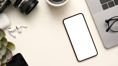 Kamera, dekor fabrikası, kulaklıklar, gözlük, dizüstü bilgisayar ve beyaz arka planda cep telefonu beyaz ekran modeliyle çalışma alanı. 