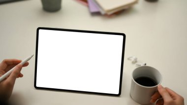 Yakın plan, stilus kalem ve kahve fincanı tutan kadın eller, işe yarar ekrandaki tablet dokunmatik ekranlara bakıyor. tablet boş ekran modellemesi.