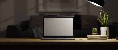 Modern karanlık ev çalışma masası oturma odasında portatif dizüstü bilgisayarlı boş ekran maketi ve masa lambasının ışıklarının altındaki ahşap masa üzerindeki alanı kopyalamak. 3d görüntüleme, 3d illüstrasyon