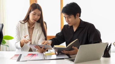 İki tasarımcı birlikte çalışarak projenin tasarım planlarını ve iç planlarını tartışıyorlar.