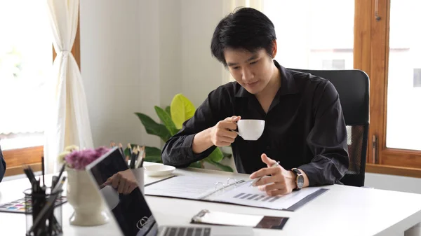 Όμορφος Και Έξυπνος Ασιάτης Νεαρός Επιχειρηματίας Πίνοντας Καφέ Κοιτάζοντας Οικονομικά — Φωτογραφία Αρχείου