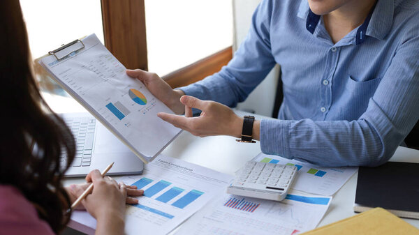 Close-up image, Male marketing manager showing the business model graph and chart report to his female boss in the office.