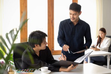 İki işadamı ofis işyerindeki pazarlama projesi hakkında konuşuyor ve fikirlerini paylaşıyorlar..