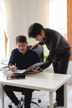 İki zeki Asyalı grafik tasarımcı ofis işyerinde çalışıyor. Erkek bir grafik tasarımcısı iş arkadaşının işine yardım eder..