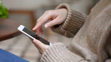 Yan görüş, parkta oturan ve rahatlayan bir kadın, akıllı telefon kullanıyor, arkadaşlarıyla sohbet ediyor..