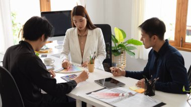 Grafik tasarımcıları ekibi ofiste ciddi bir toplantı yapıyor, renk örneklerinde şablon rengini tartışıyor ve seçiyorlar.