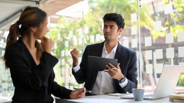 Yakışıklı bir Asyalı erkek patron ofisteki kadın çalışanı cesaretlendirir ve güçlendirir. Neşelen el hareketi.