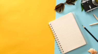 Metinlerinizi, seyahat aksesuarlarınızı ve mavi ve sarı arkaplandaki kopyalama alanını göstermek için boş günlük kapağı modeli. Üst görünüm, yaz tatili kompozisyon arkaplanı