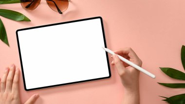 Kadınsı pembe çalışma alanı konsepti, tablet ekranına stilus kalemle kadın eli çizimi. yukarıda