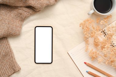 Akıllı telefon beyaz ekran modeliyle rahat, kadınsı ofis çalışma alanı kompozisyonu. en üstteki görünüm