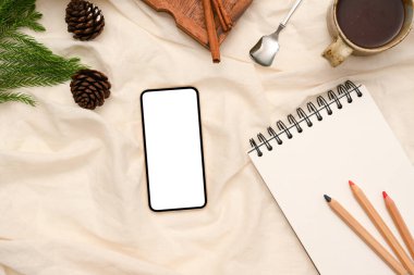 Beyaz arka planda spiral not defteri, renk kalemi ve aksesuarları olan akıllı telefon boş beyaz ekran modeli. en üstteki görünüm