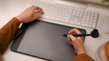 Yakın plan resim, kadın serbest grafik tasarımcısı veya grafik tablet üzerinde çalışan ve ofis masasında çalışan fotoğraf editörü.