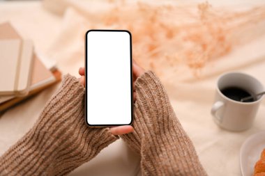 Bulanık ofis masasının arka planında bir kadının elindeki akıllı telefon beyaz ekran modeli..
