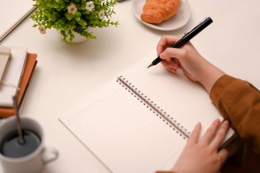 Yakın plan görüntü, ev ödevini yapan kız öğrenci, spiral okul defterine bir şeyler yazıyor..