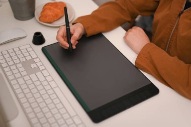 Ofis masasında grafik tablet ve stil kalem kullanan kadın grafik tasarımcısı ya da fotoğraf editörü. odaklan.