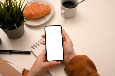 Modern beyaz çalışma alanı arkaplanı üzerinden kadınların elinde akıllı telefon beyaz ekran modeli.