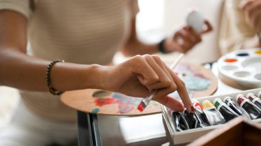 Yakın çekim elleri, akrilik renkli bir tüp tutan kadın, çizimlerinin rengini seçiyor..