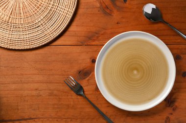 Üst manzara, düz yer, boş tabak, kaşık, çatal, bambu masa örtüsü ahşap yemek masası arka planında..