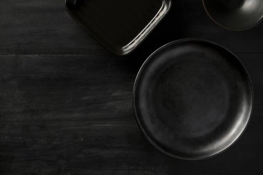 Üst görünüm, siyah seramik plaka modeli, siyah çatal bıçak ve siyah tablo arkaplanındaki boşluğu kopyala.