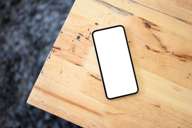 Tepedeki resim, beyaz bir akıllı telefon ekran modeli. Grafik resminiz ahşap bir masanın üzerinde.