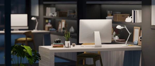 テーブル 屋内植物や組み込みの棚にコンピュータやアクセサリーと現代的なインテリアスタイルで夜のオフィスデスクワークスペース 3Dレンダリング 3Dイラスト — ストック写真