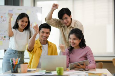 Başarılı Asyalı genç girişim grubu ofis toplantı odasında birlikte çalışıyor ve kutluyor..