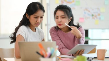 Güzel Asyalı genç iş kadınları ofis işyerinde projede birlikte çalışıyorlar..