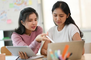 İki bayan meslektaşı, ofis masasında pazarlama projelerini tartışıyor ve planlıyorlar..