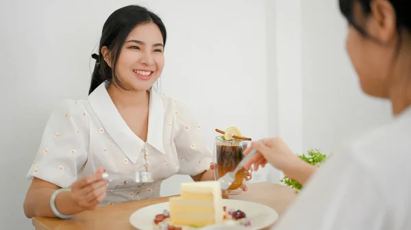 二つの幸せな千年のアジアの女性の友人は一緒にカフェでデザートを食べておしゃべりを楽しむ — ストック写真