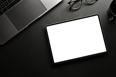 Üst görünümde, dizüstü bilgisayarı, gözlüğü ve dijital tablet beyaz ekran modeliyle modern minimal siyah çalışma alanı.