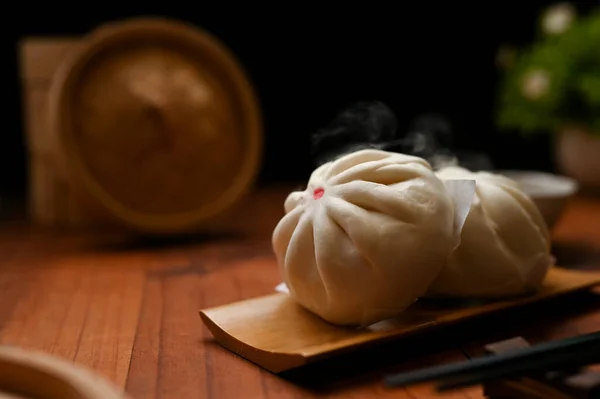 Tasty hot steamed meat or pork buns on a wooden plate. Traditional Chinese cuisine concept, closeup.