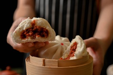Kırpılmış, elinde bambu buharı ve buğulanmış domuz buğulama ekmeği tutan kadın aşçı. Asya Çin yemeği konsepti.