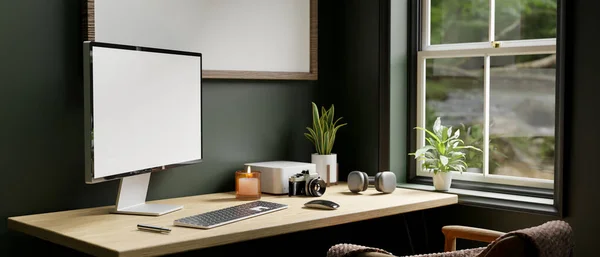 パソコンのデスクトップコンピュータのモックアップ カメラ ヘッドフォン キーボードとフレームモックアップと濃い緑の壁の上のテーブルの上にアクセサリーと現代のホームオフィスワークスペース 3Dレンダリング 3Dイラスト — ストック写真