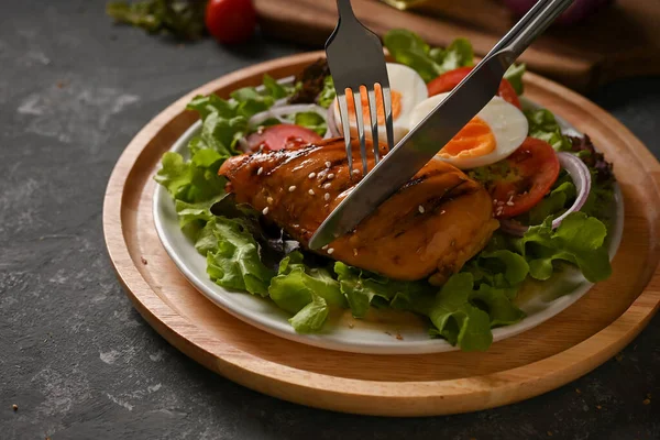Yakın plan görüntü, kadın çatal bıçak kullanarak ızgara teriyaki tavuğu ve salata karışımı yiyor. Sağlıklı salata yemeği.